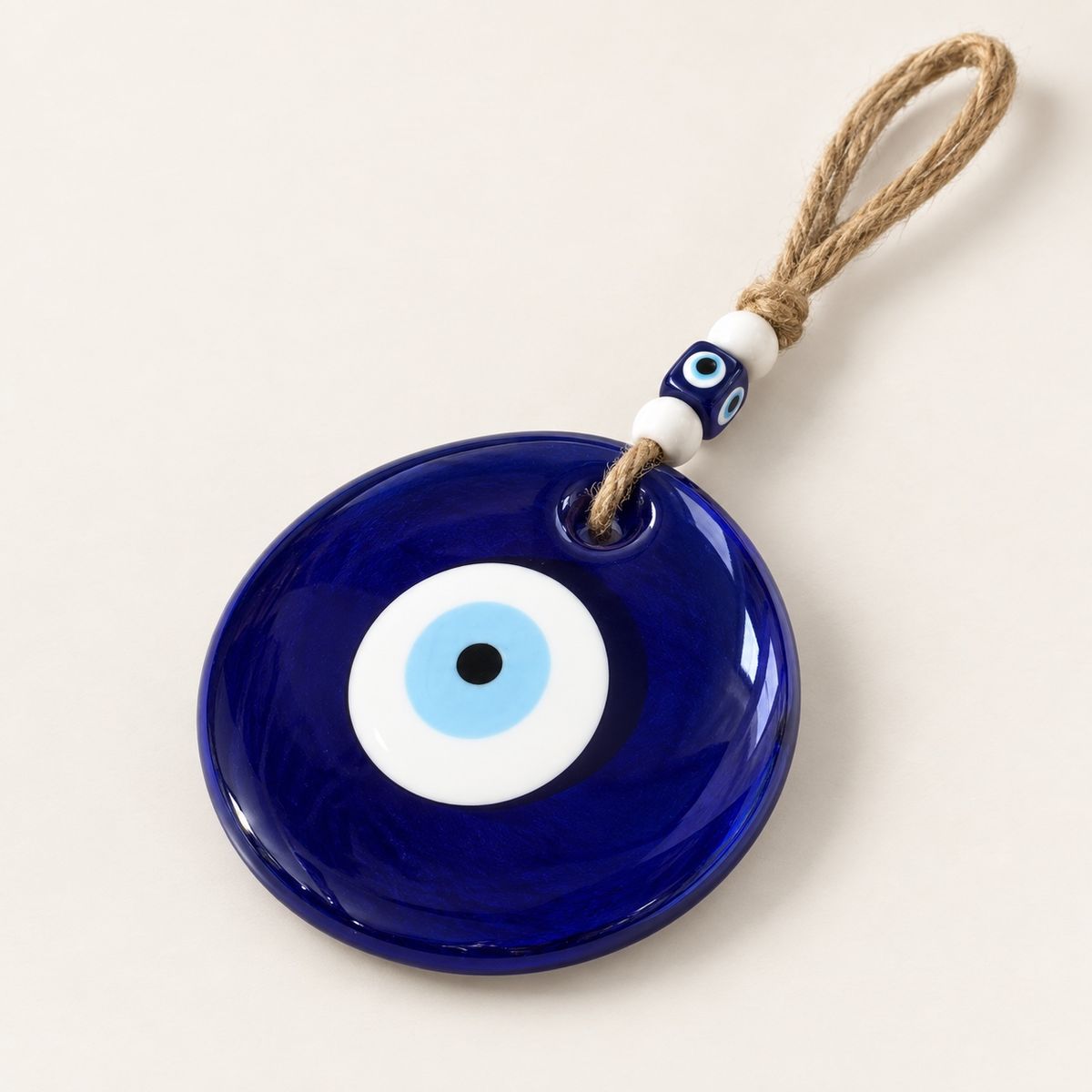 Angled close-up of the round blue glass evil eye, jute loop and bead details