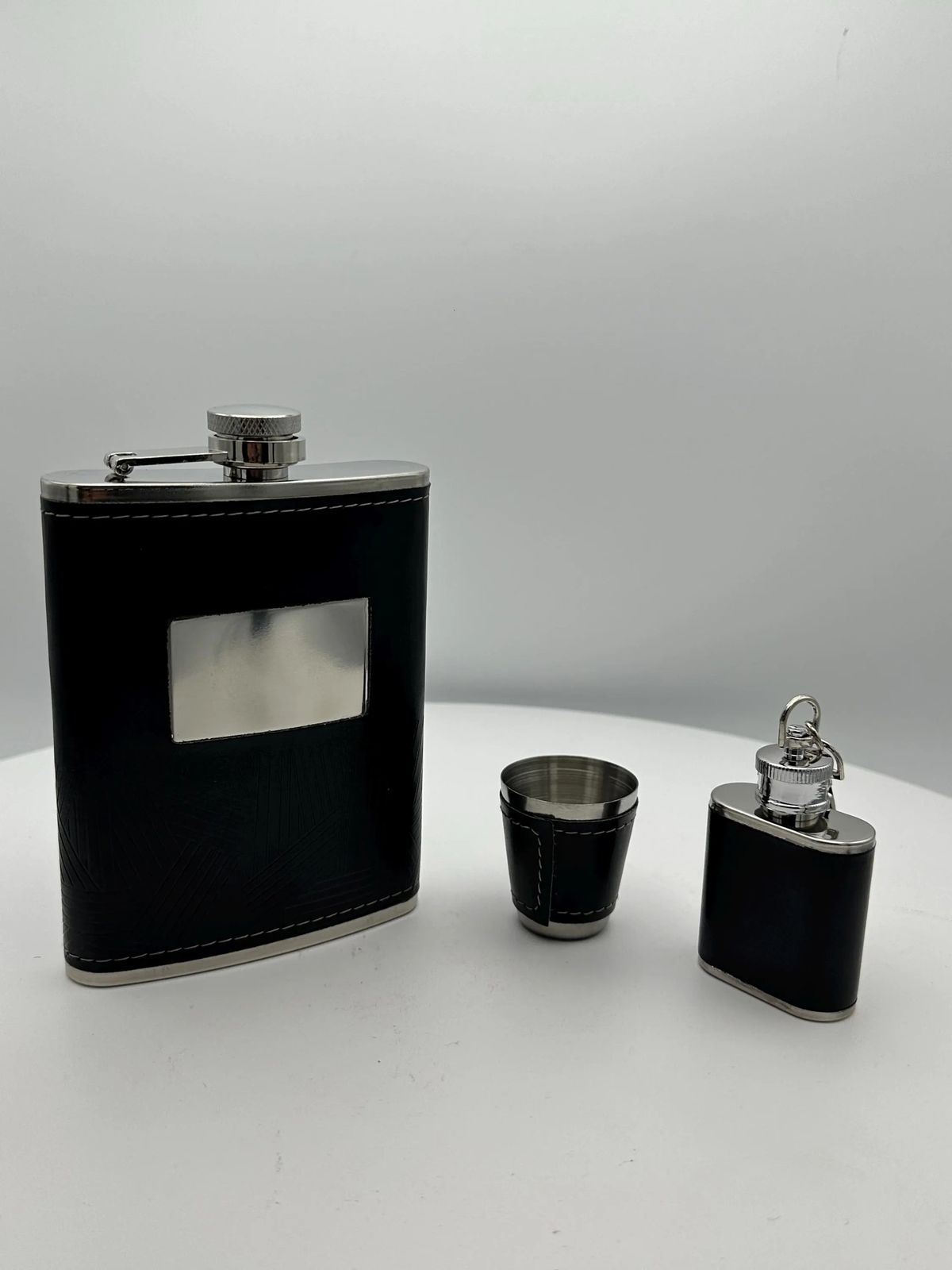 Große und kleine Flasche mit Schnapsbecher.